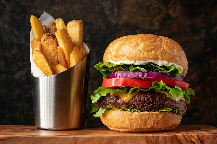 Burger garni de salade et de tomate, servi avec des frites (photo d'illustration)