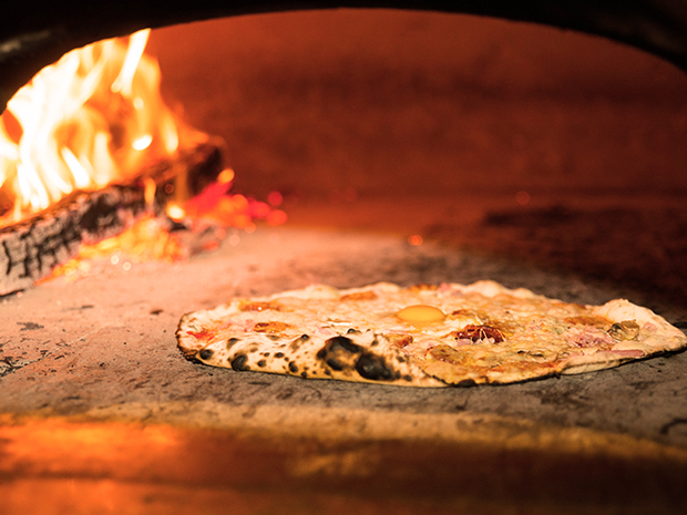 Photo du restaurant : une pizza qui cuit dans le four à bois de La Pinède